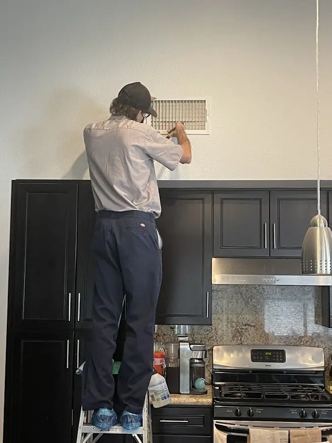 Technician inspecting an air vent during HVAC service in Raceland